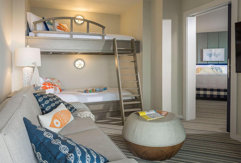 Bunk beds with a steel ladder and safety railing and a cozy couch