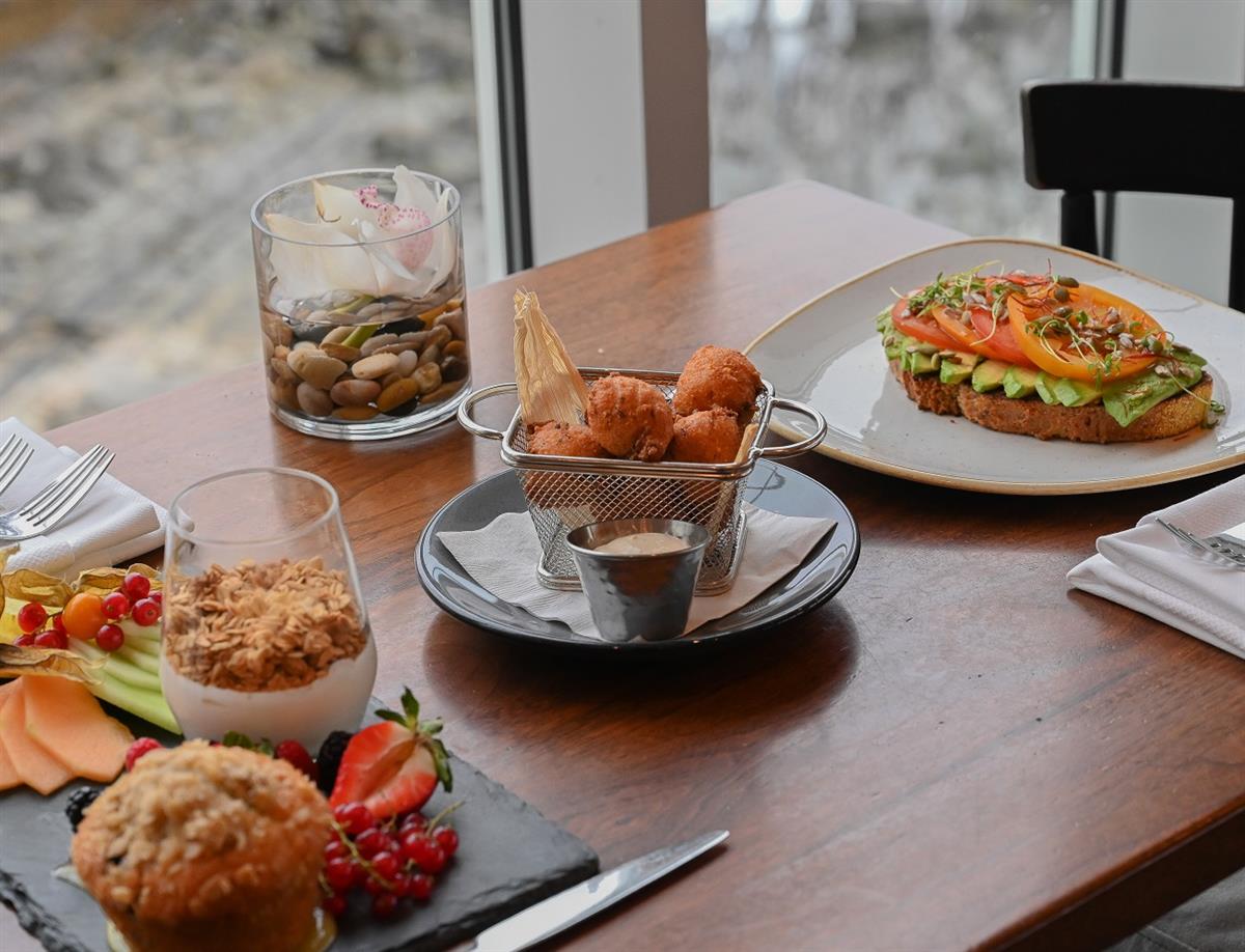 Breakfast with a yogurt parfait, a muffin, fresh fruit, and avocado toast